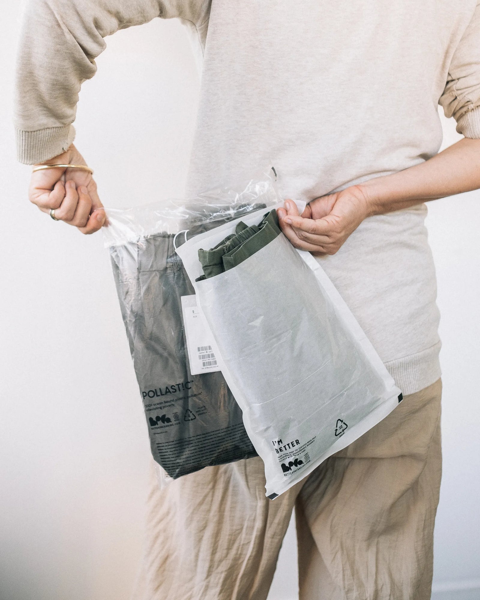Person holding a POLLAST!C Poly Garment Bag and Glassine Garment Bag behind their back